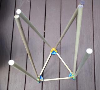 A truss made of wood dowels and colurful 3D printed pieces in a triangle