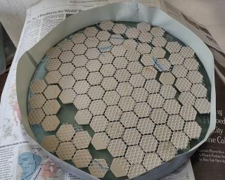 My mirror with tiles laid on top and a row of duct tape around the edges. I mix dental stone powder with water and pour it on top, where it hardens into a tool with the same shape as the mirror's curve.