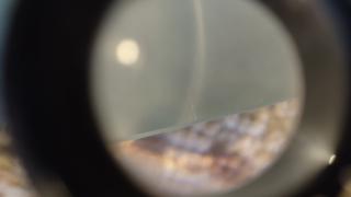 Tiny scratches visible near where the light ray intersects the mirror's edge and a bit further along the edge to the right.