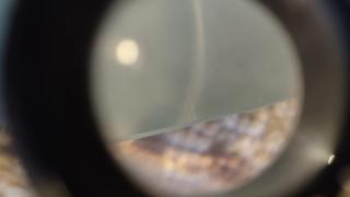 Tiny scratches visible near where the light ray intersects the mirror's edge and a bit further along the edge to the right.