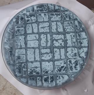 Looking top down on a stack. From top to bottom: mirror (currently a piece of glass, but it'll become a mirror), cerium oxide polishing compound (white), black pitch tool. The white in the center shows there's a slight gap between the pitch and the mirror.