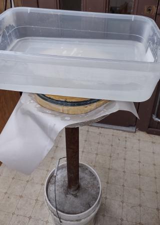 A tub of hot water is used as a weight to press the pitch to the mirror so the pitch takes on the mirror's shape