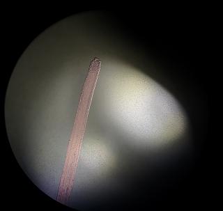 The mirror under a microscope. The sharpie line looks purple. Notice the texture next to the sharpie - tons of tiny dots, divots left from 5 micron grinding that I'll need to grind through to get a smooth polished surface.